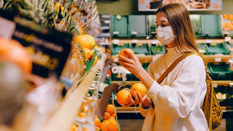 Une femme achète des fruits avec un masque de protection
