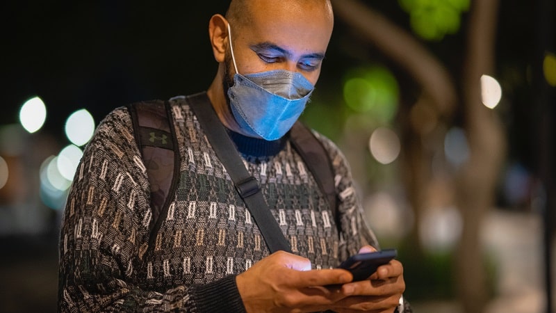 Un utilisateur d'iPhone avec un masque de protection