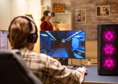 Back view of professional video gamer playing on powerful PC late at night in the living room